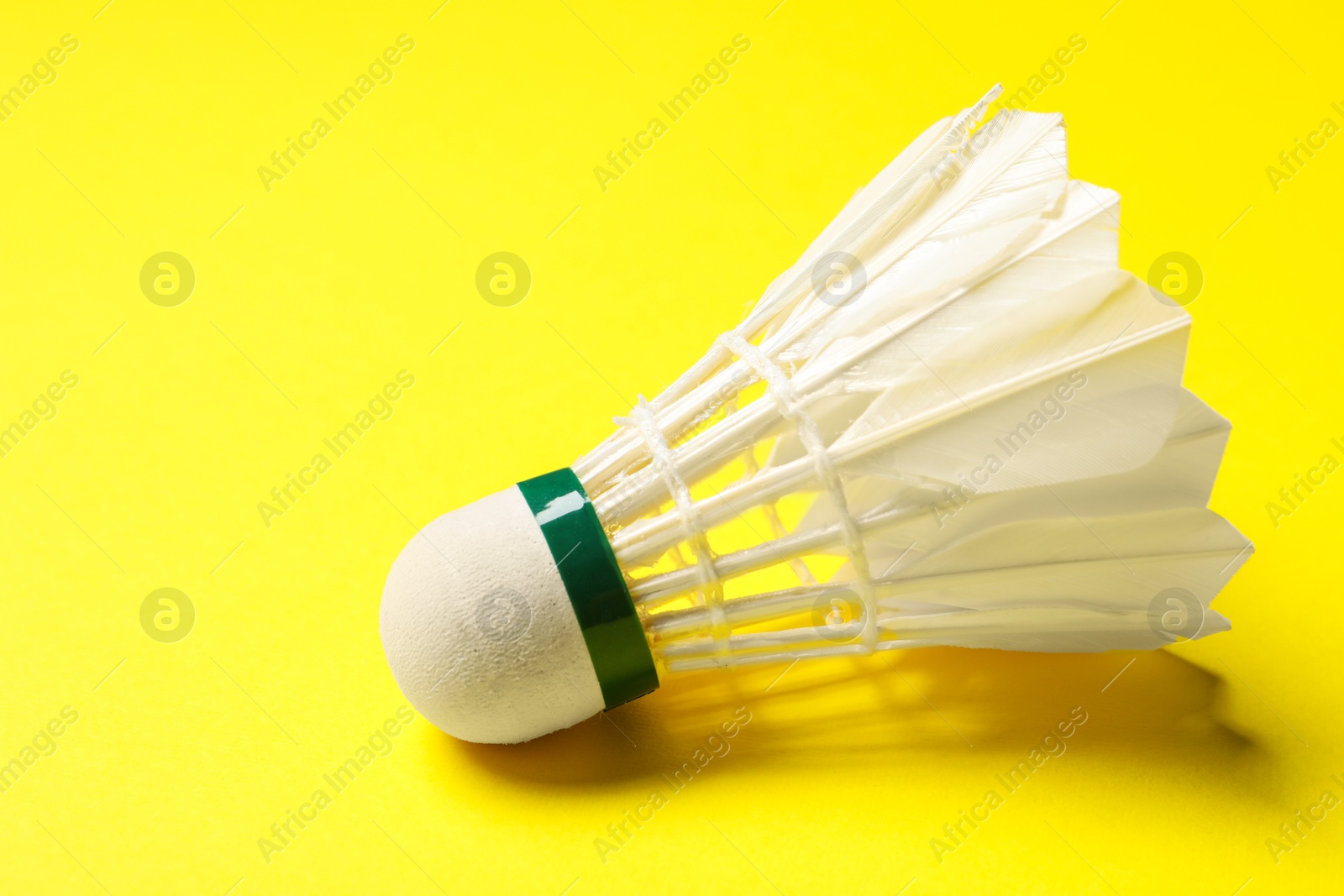 Photo of One feather badminton shuttlecock on yellow background