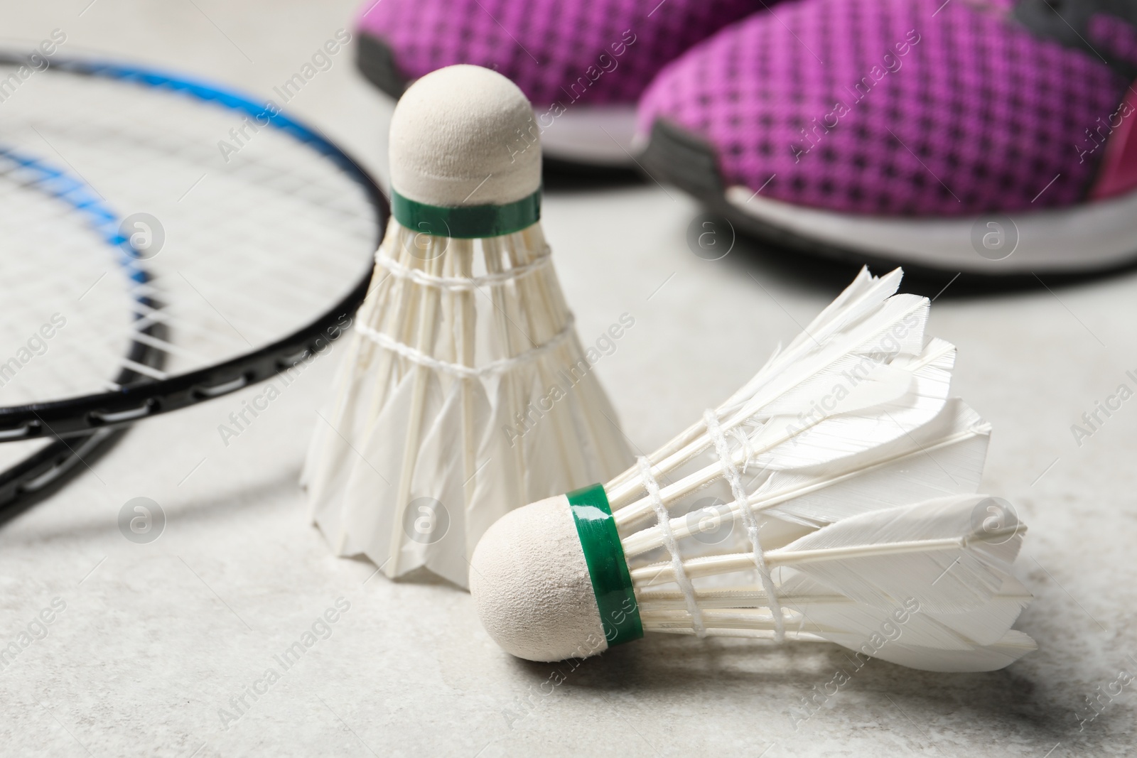 Photo of Feather badminton shuttlecocks, rackets and sneakers on gray background, closeup