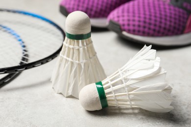 Feather badminton shuttlecocks, rackets and sneakers on gray background, closeup