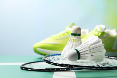 Photo of Feather badminton shuttlecocks and rackets on court, space for text