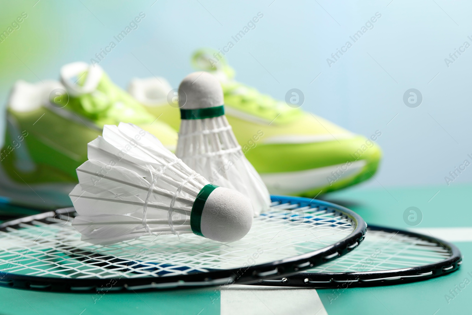 Photo of Feather badminton shuttlecocks and rackets on court, closeup