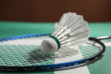 Photo of Feather badminton shuttlecock and racket on court, closeup