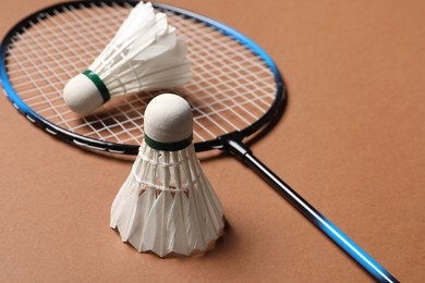 Feather badminton shuttlecocks and racket on brown background, closeup