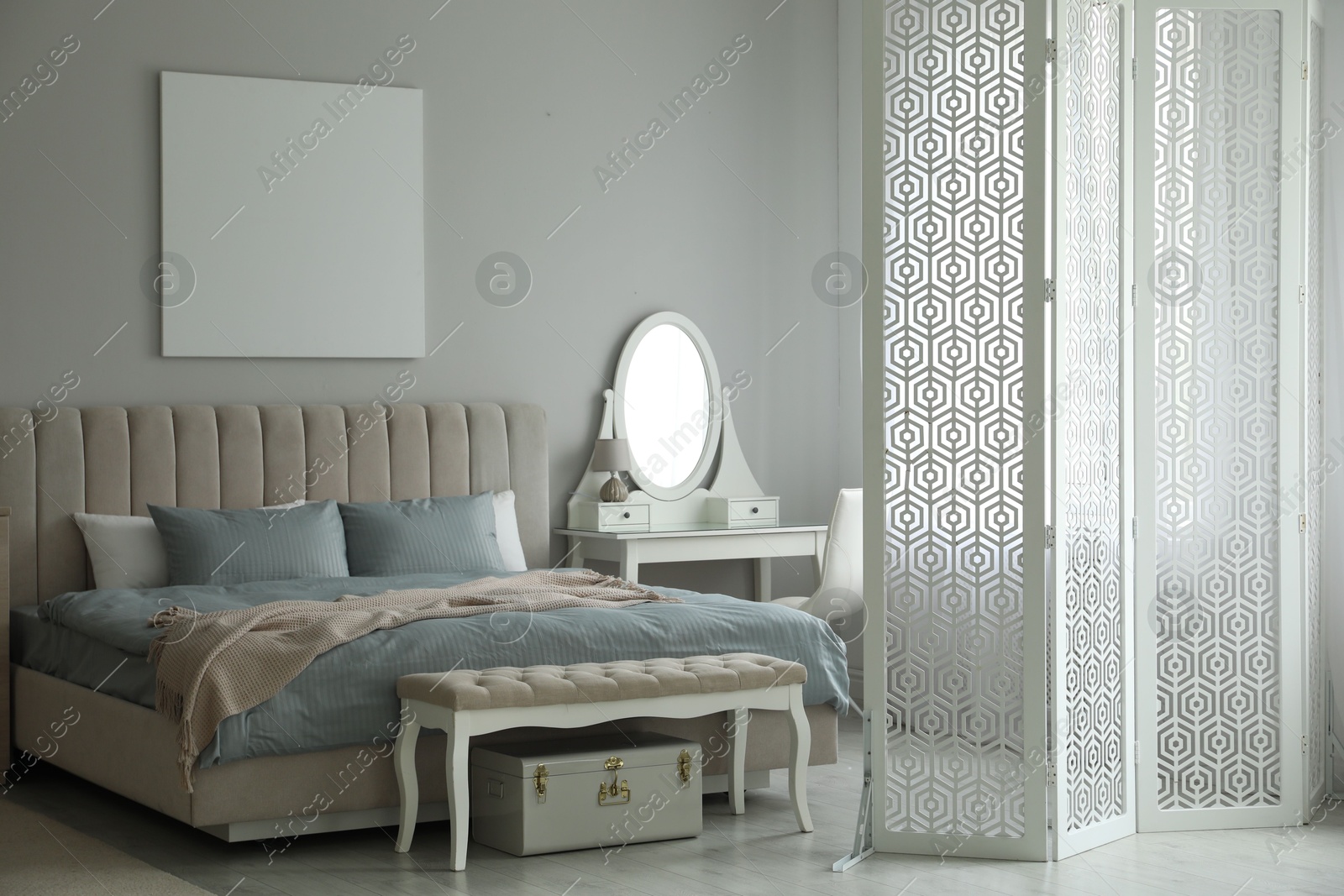 Photo of Folding screen, mirror and comfortable bed in bedroom. Interior design