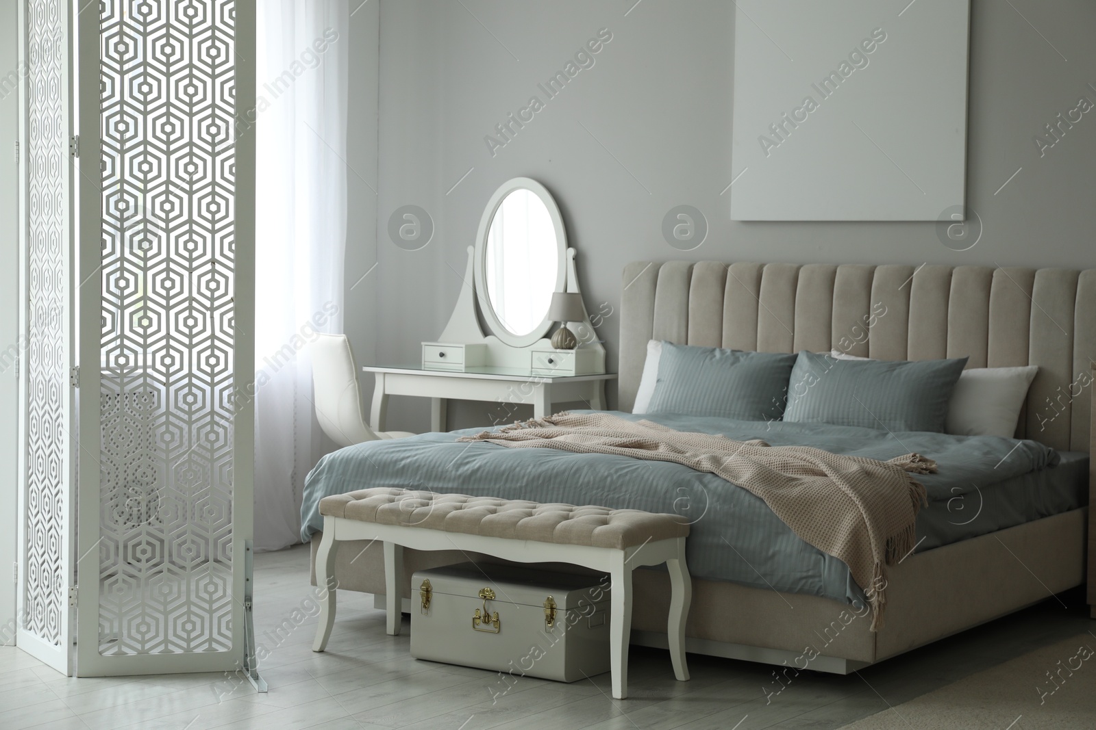 Photo of Folding screen, mirror and comfortable bed in bedroom. Interior design