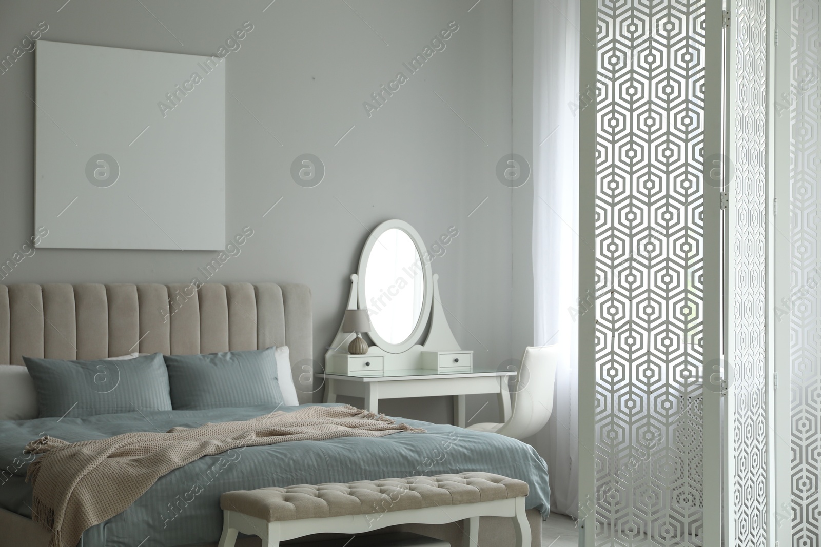 Photo of Folding screen, mirror and comfortable bed in bedroom. Interior design