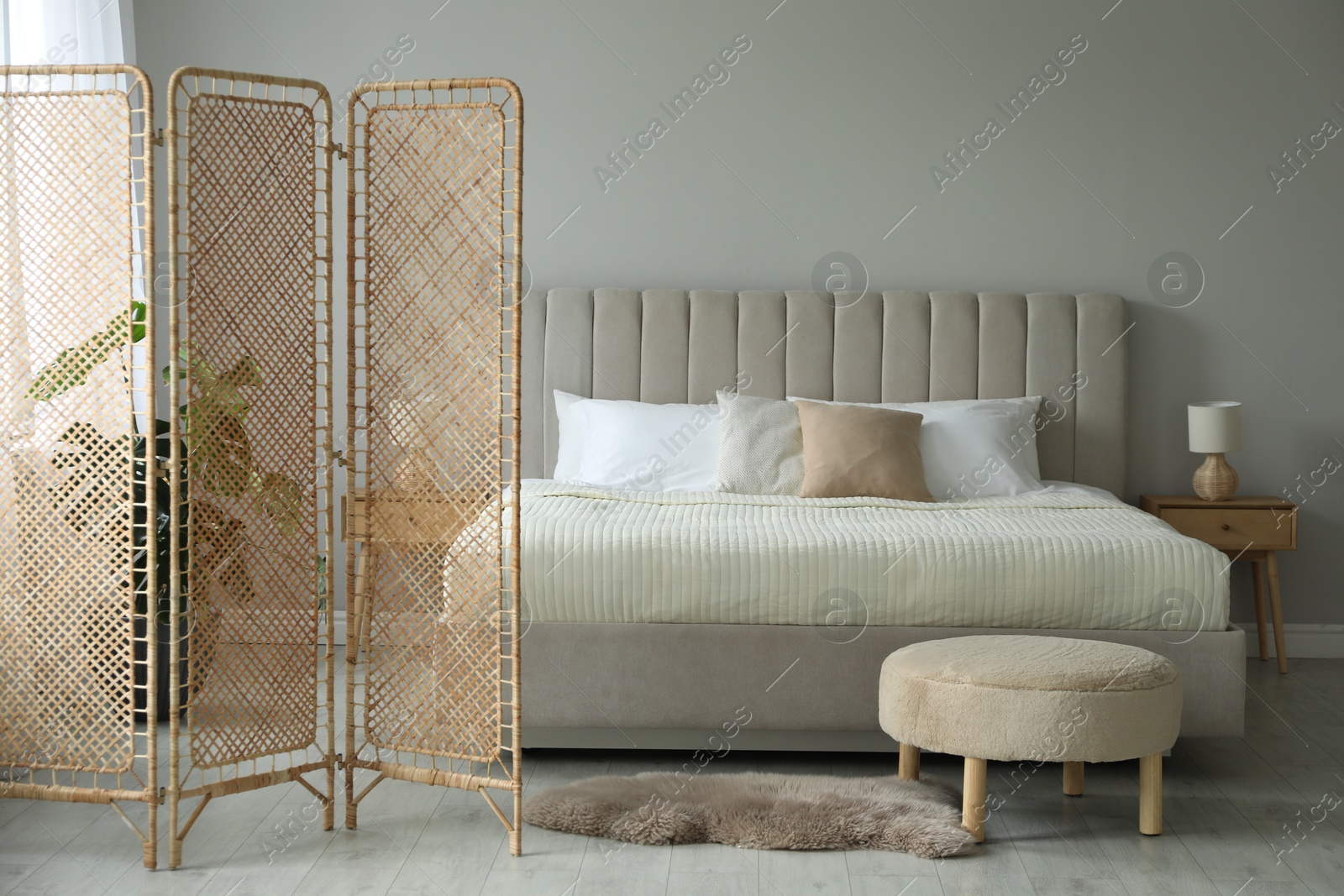 Photo of Folding screen and comfortable bed in bedroom. Interior design