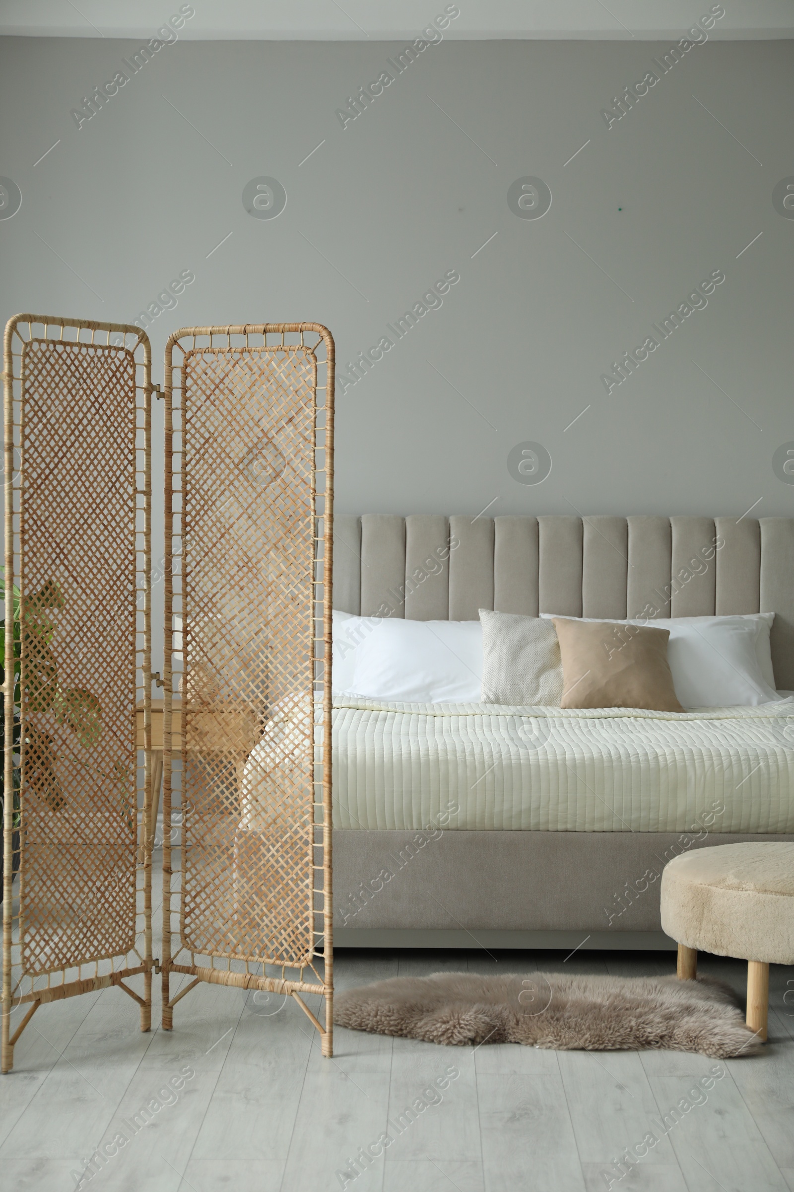 Photo of Folding screen and comfortable bed in bedroom. Interior design