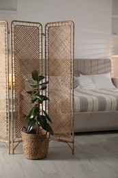 Photo of Folding screen and comfortable bed in bedroom. Interior design