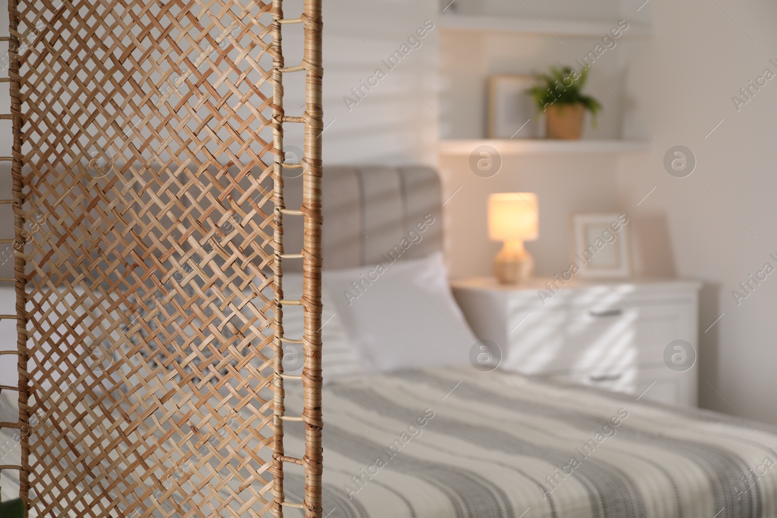 Photo of Folding screen and comfortable bed in bedroom, closeup. Space for text