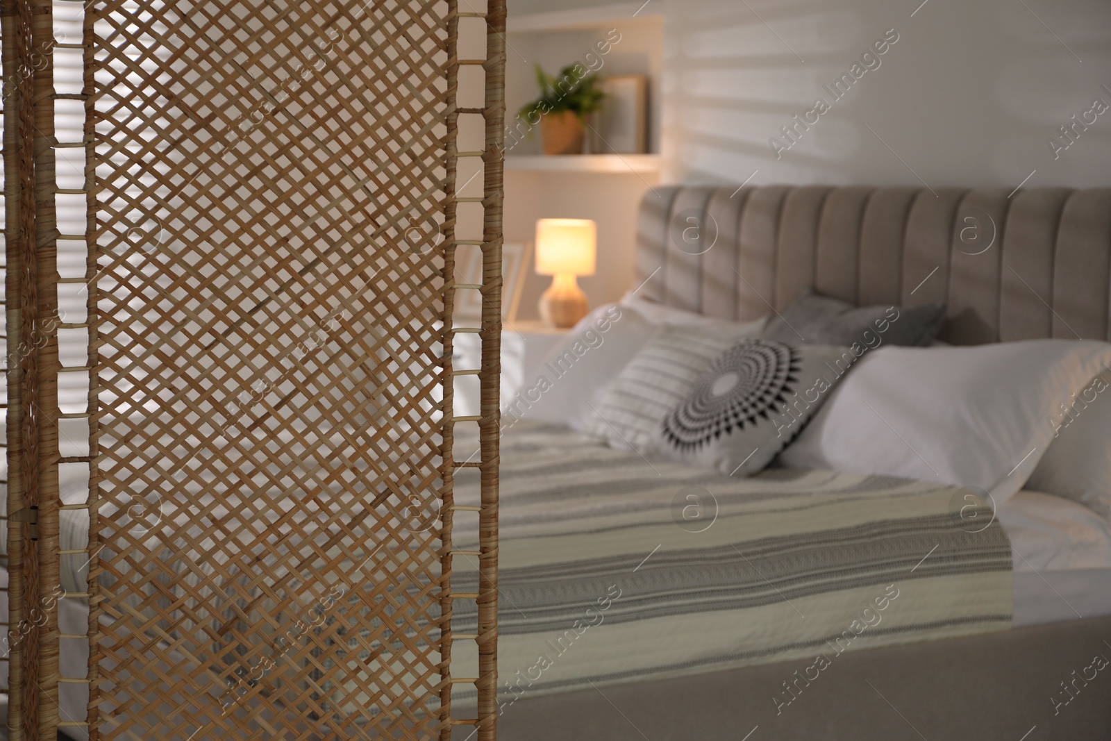 Photo of Folding screen and comfortable bed in bedroom, closeup. Space for text