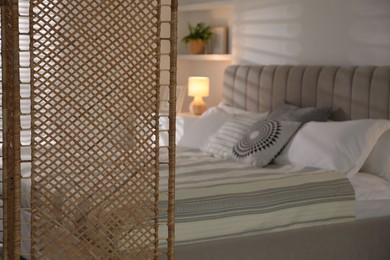 Photo of Folding screen and comfortable bed in bedroom, closeup. Space for text