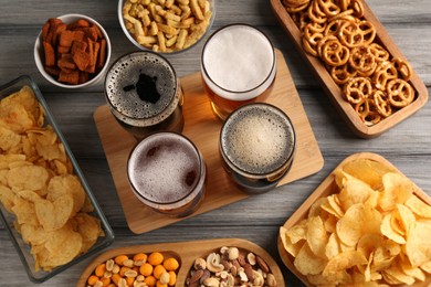 Photo of Glasses with different types of beer and snacks on grey wooden table, flat lay