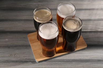 Photo of Glasses with different types of beer on grey wooden table