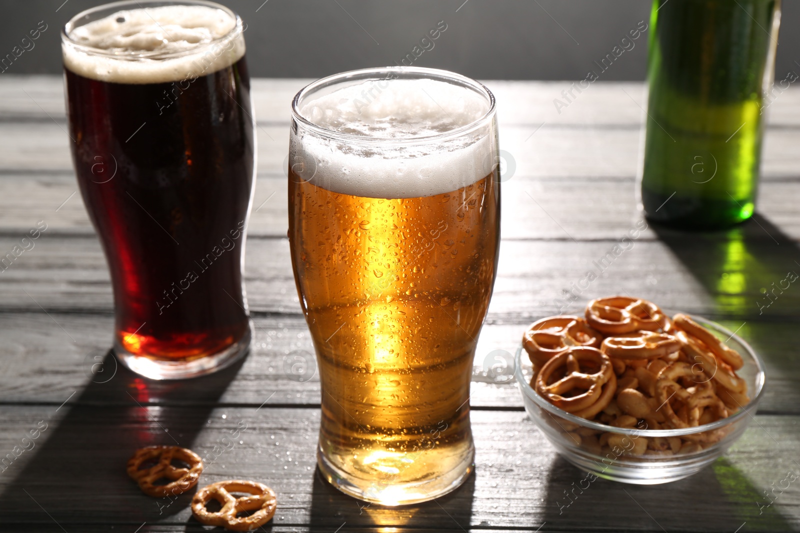 Photo of Glasses of beer and pretzel crackers on grey wooden table