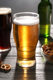 Glasses of beer and pretzel crackers on grey wooden table