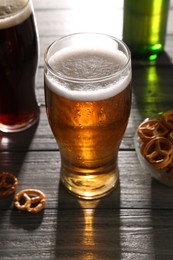 Glasses of beer and pretzel crackers on grey wooden table