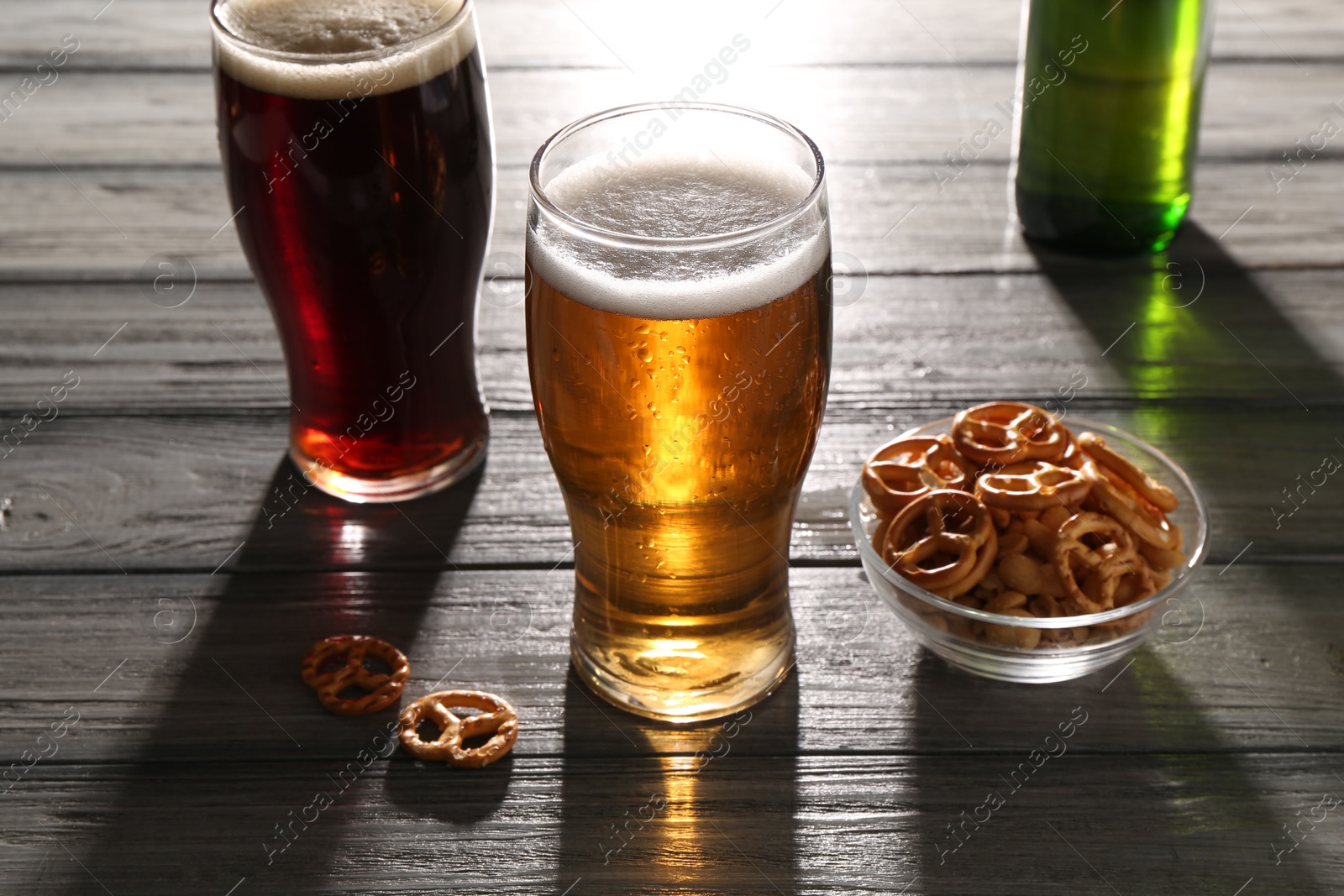 Photo of Glasses of beer and pretzel crackers on grey wooden table