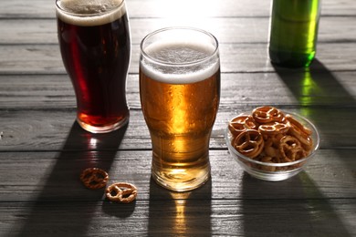 Photo of Glasses of beer and pretzel crackers on grey wooden table