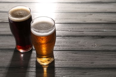 Glasses with different types of beer on grey wooden table, space for text