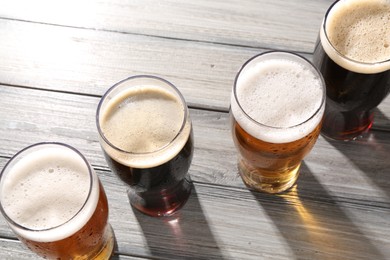 Glasses with different types of beer on grey wooden table, above view