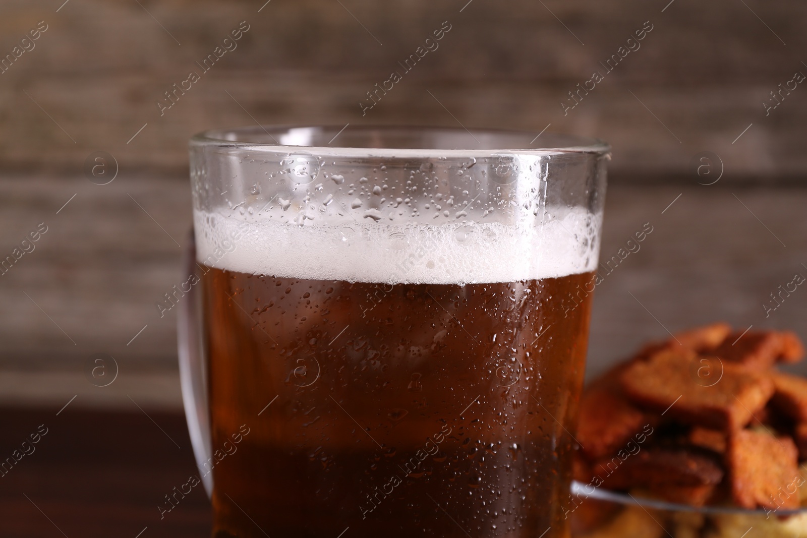 Photo of Glass mug of beer and rusks on wooden table