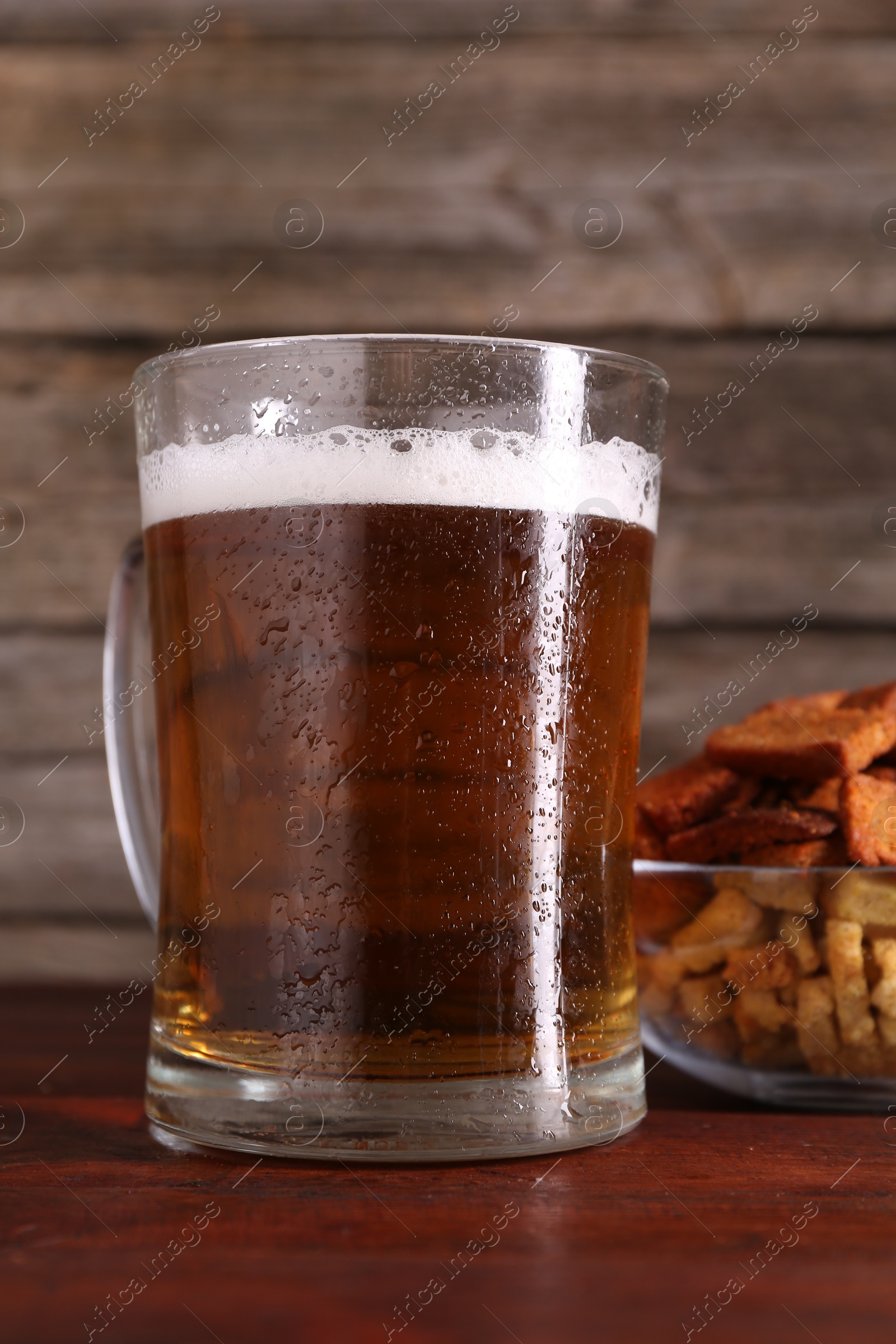 Photo of Glass mug of beer and rusks on wooden table