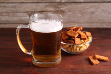 Photo of Glass mug of beer and rusks on wooden table