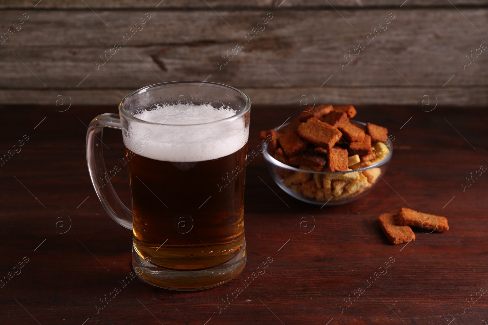 Photo of Glass mug of beer and rusks on wooden table