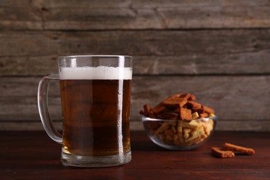 Photo of Glass mug of beer and rusks on wooden table