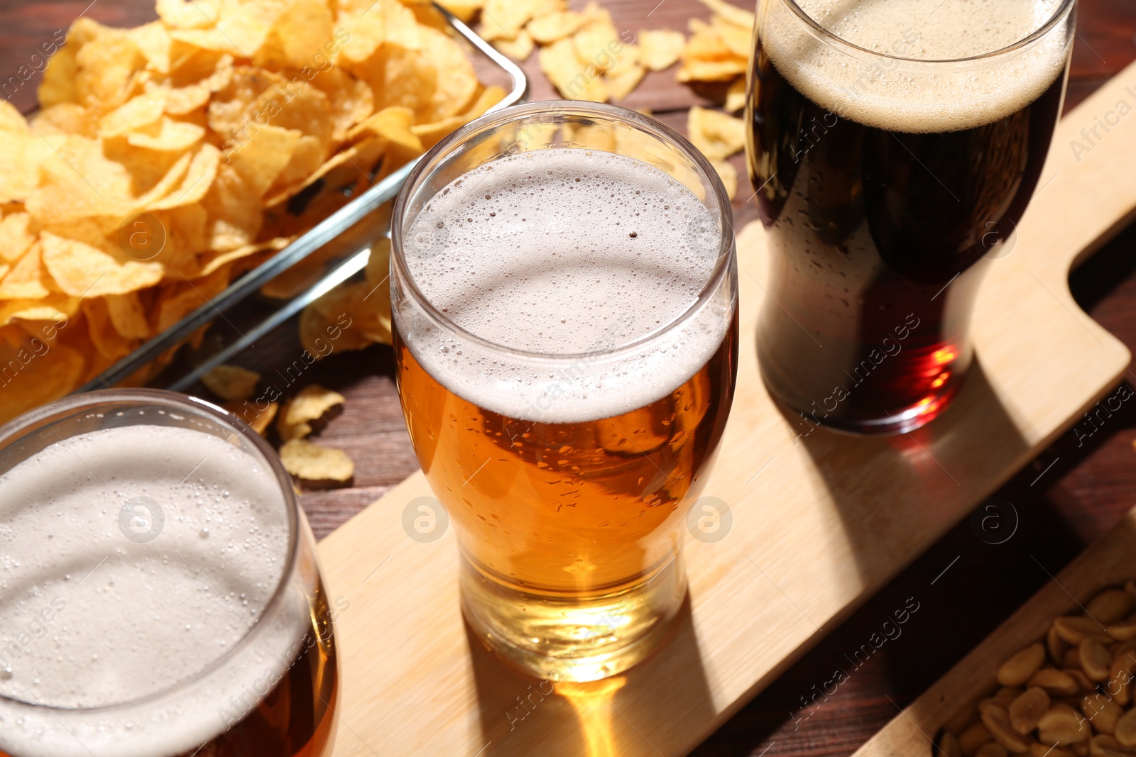 Photo of Glasses of beer and snacks on wooden table, closeup