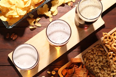 Glasses of beer and snacks on wooden table, flat lay