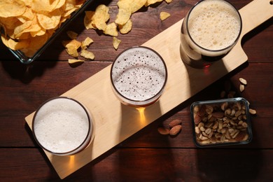 Photo of Glasses of beer and snacks on wooden table, flat lay