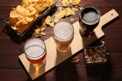 Glasses of beer and snacks on wooden table, flat lay