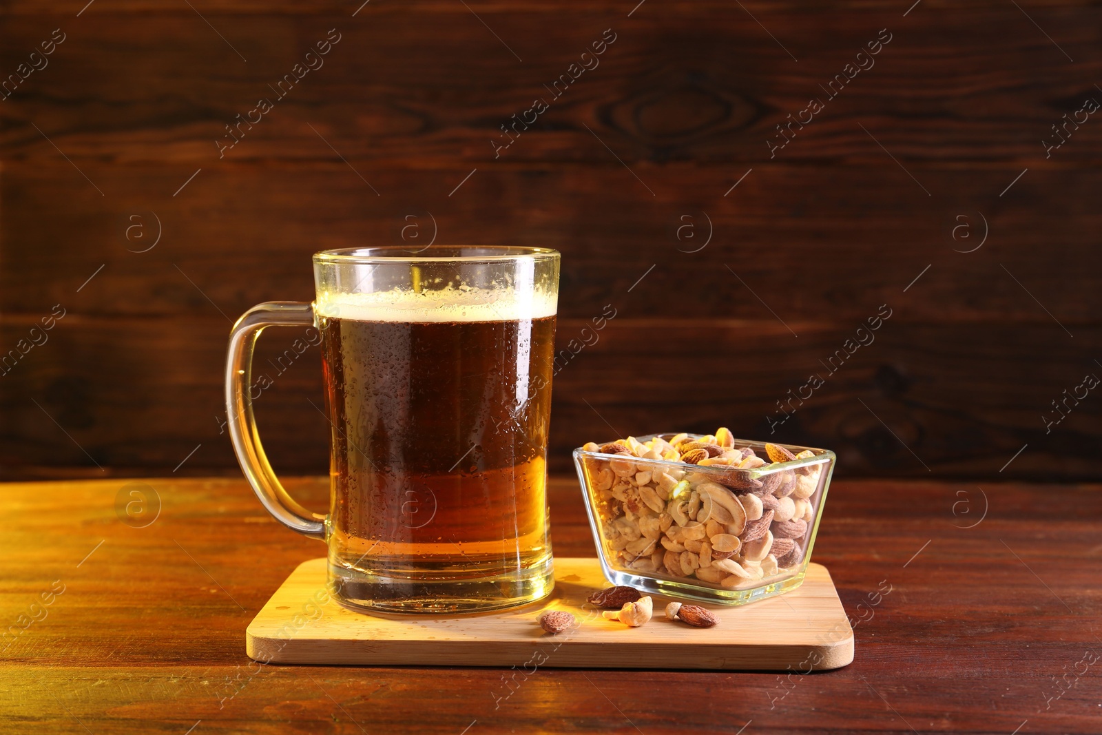 Photo of Glass mug of beer and nuts on wooden table