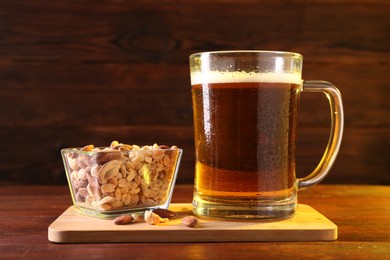 Photo of Glass mug of beer and nuts on wooden table