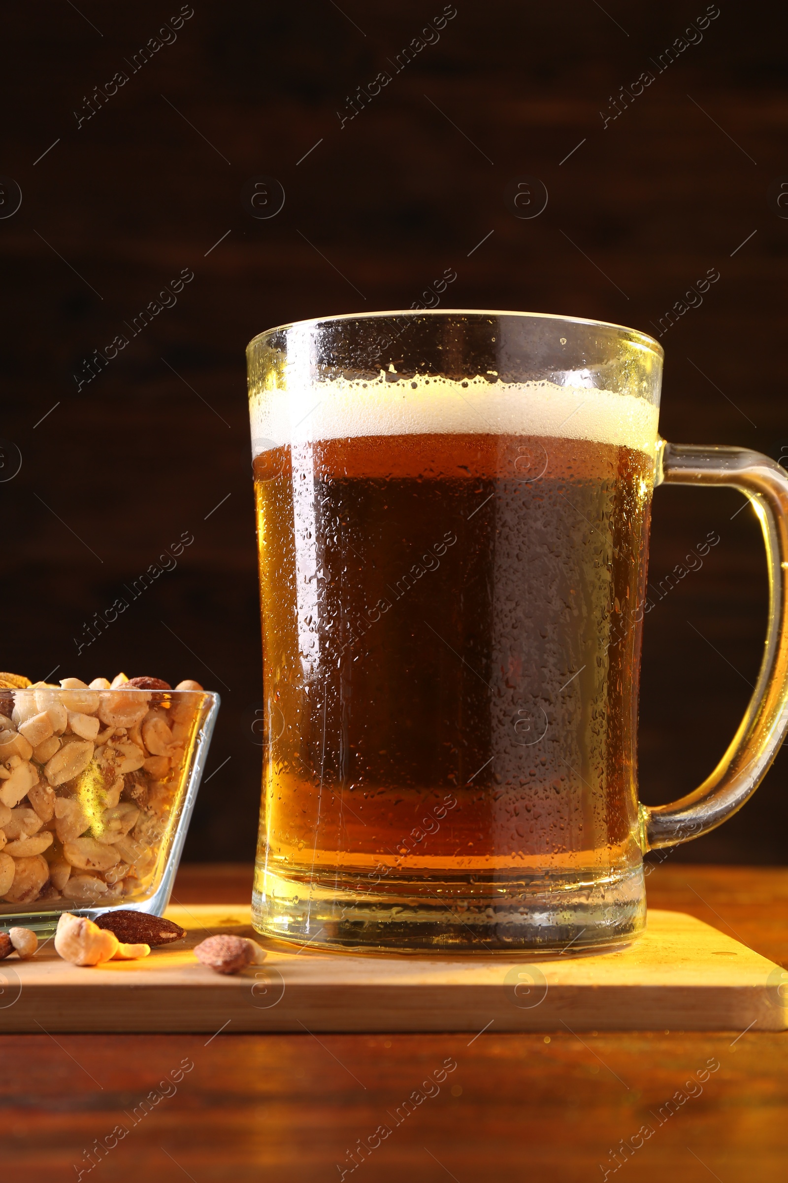 Photo of Glass mug of beer and nuts on wooden table