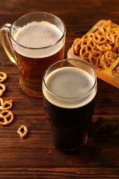 Glasses with different types of beer and snacks on wooden table