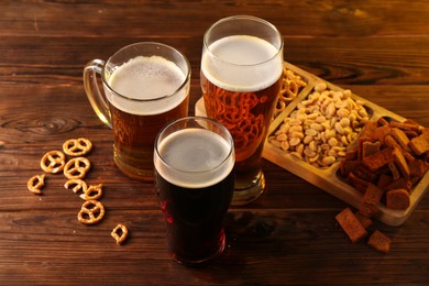 Photo of Glasses with different types of beer and snacks on wooden table