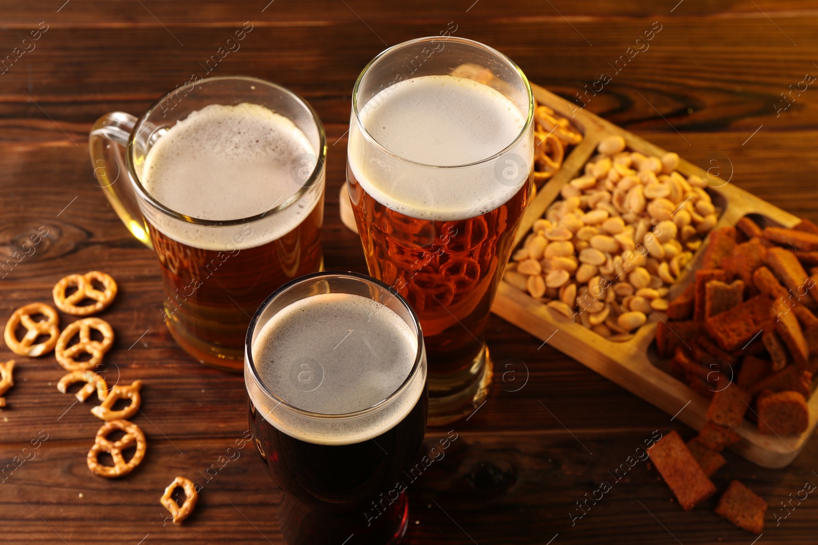 Photo of Glasses with different types of beer and snacks on wooden table