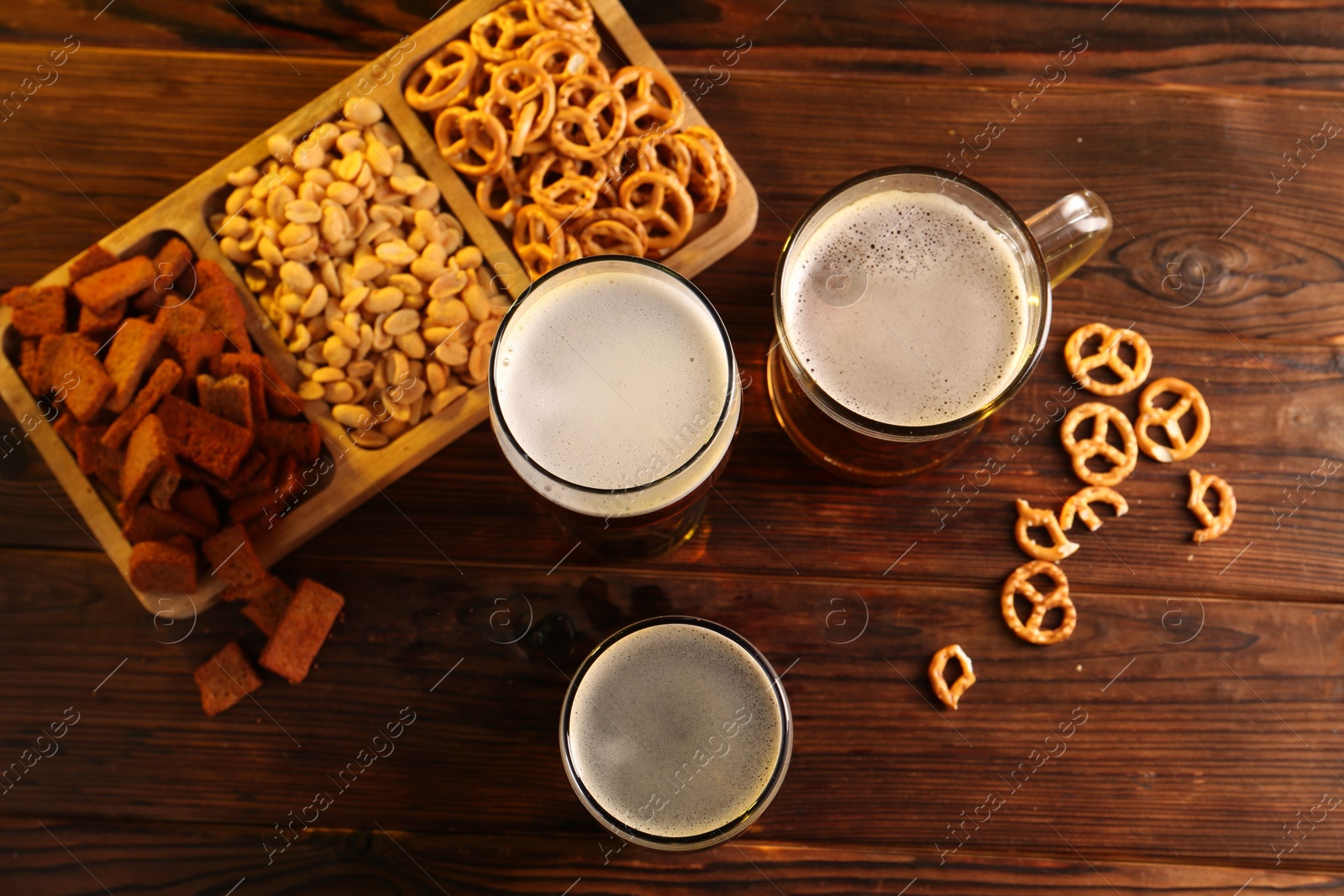 Photo of Glasses with different types of beer and snacks on wooden table, flat lay