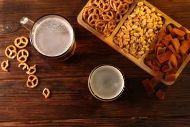 Photo of Glasses with different types of beer and snacks on wooden table, flat lay