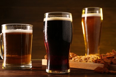 Glasses with different types of beer and snacks on wooden table