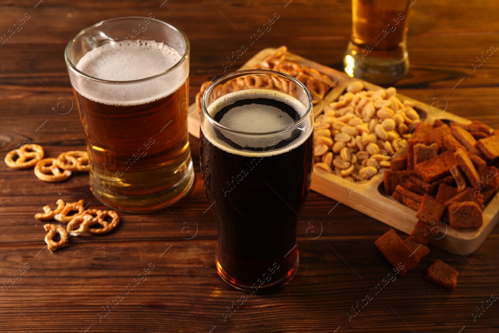 Photo of Glasses with different types of beer and snacks on wooden table