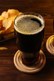 Photo of Glass of beer and potato chips on wooden table, closeup