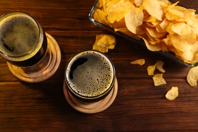 Glasses of beer and potato chips on wooden table