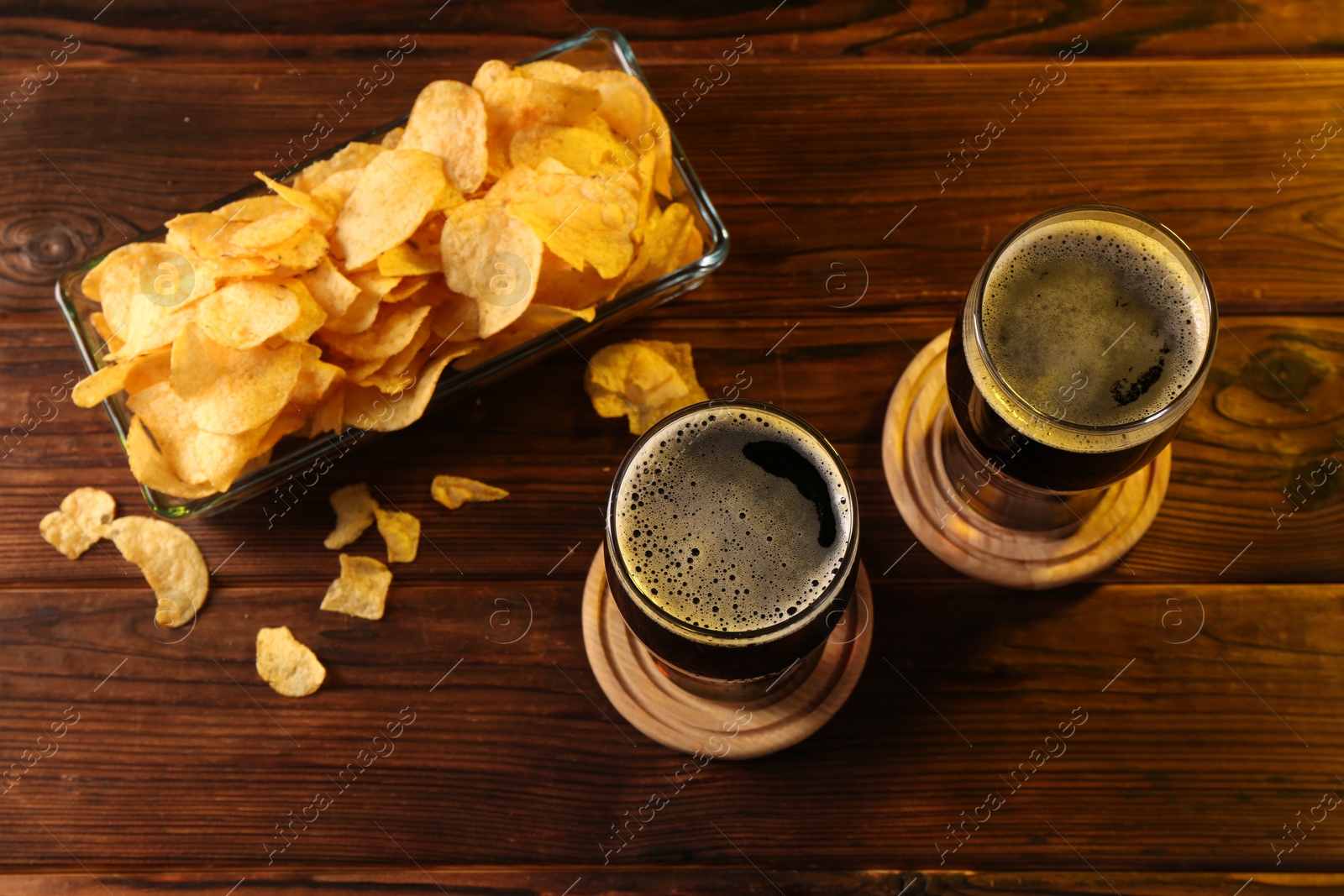 Photo of Glasses of beer and potato chips on wooden table