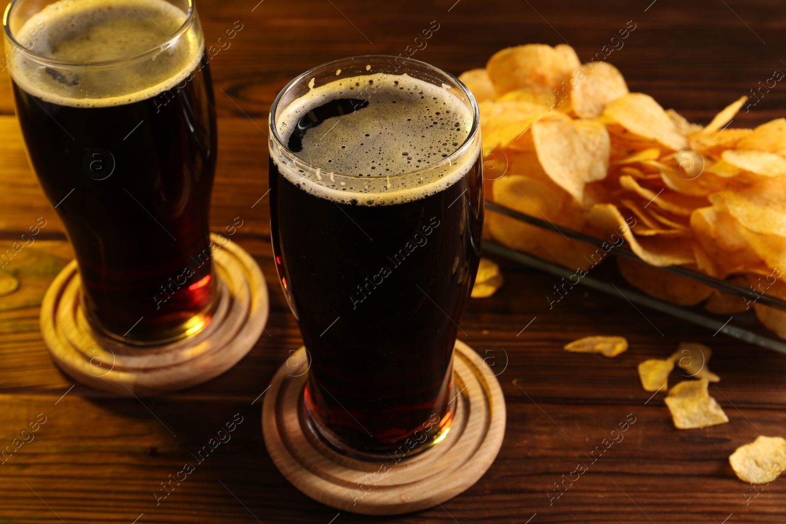 Photo of Glasses of beer and potato chips on wooden table