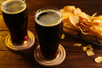 Glasses of beer and potato chips on wooden table