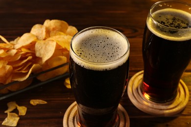 Photo of Glasses of beer and potato chips on wooden table, closeup